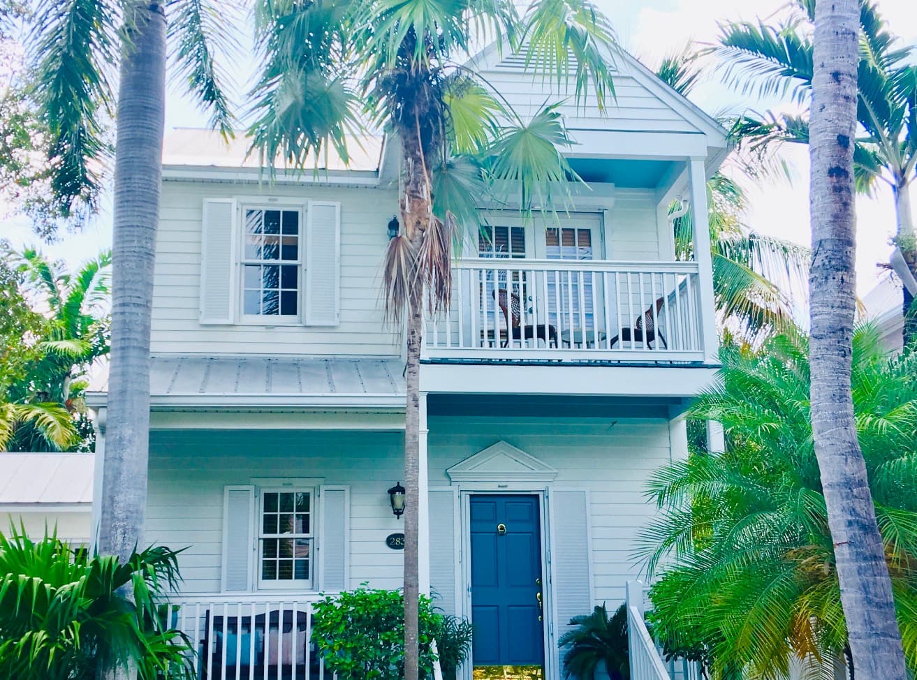 A Key West Golf Club home with palms, porches, and a blue front door